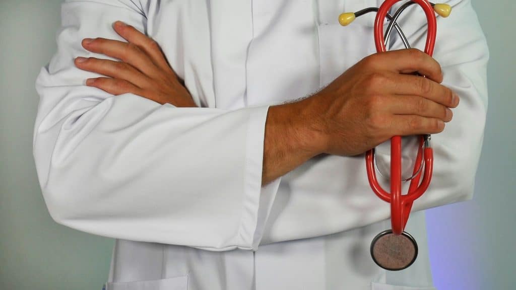man holding a stethoscope with his arms folded across his chest wearing a white lab coat.